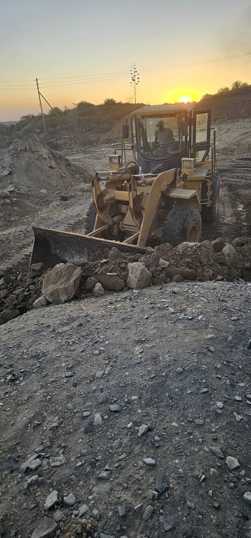 Wheel loader clearing rock at sunset
